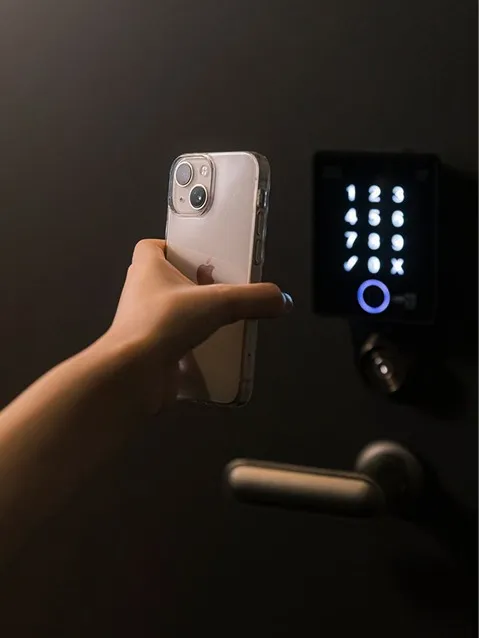 スマートフォンをドアの電子ロックにかざす様子。