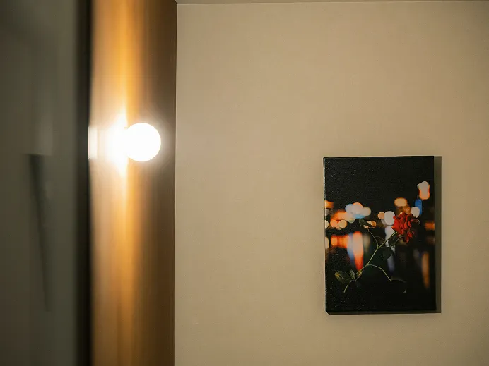 丸い球形の壁掛けライトが灯る壁面。そばに赤い花を描いた絵画が飾られている。