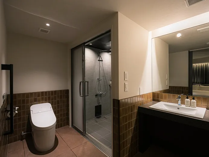 手すり付きのトイレと引き戸、洗面カウンターを配した、バリアフリーに配慮したバスルーム。